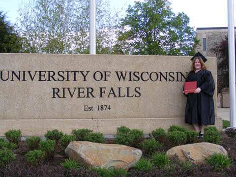 Niki Paton holding her diploma case in front of the UW-River Falls sign