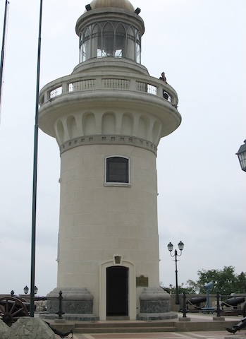 A gray lighthouse with a walkway just below the level 
     of the light