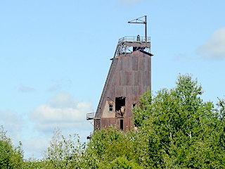 The top of the rusted tower stands above some trees