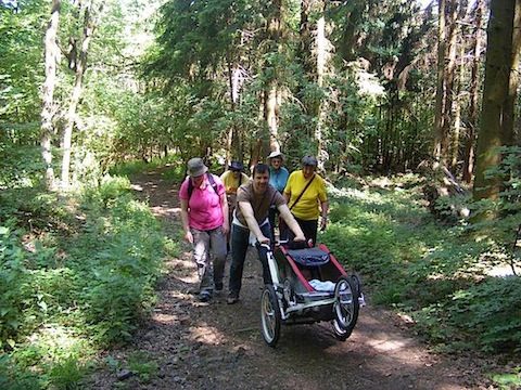 Holgar pushes the stoller/trailer containing Felix up the               rugged forest trail. The other members of our group are in              a bunch behind him.