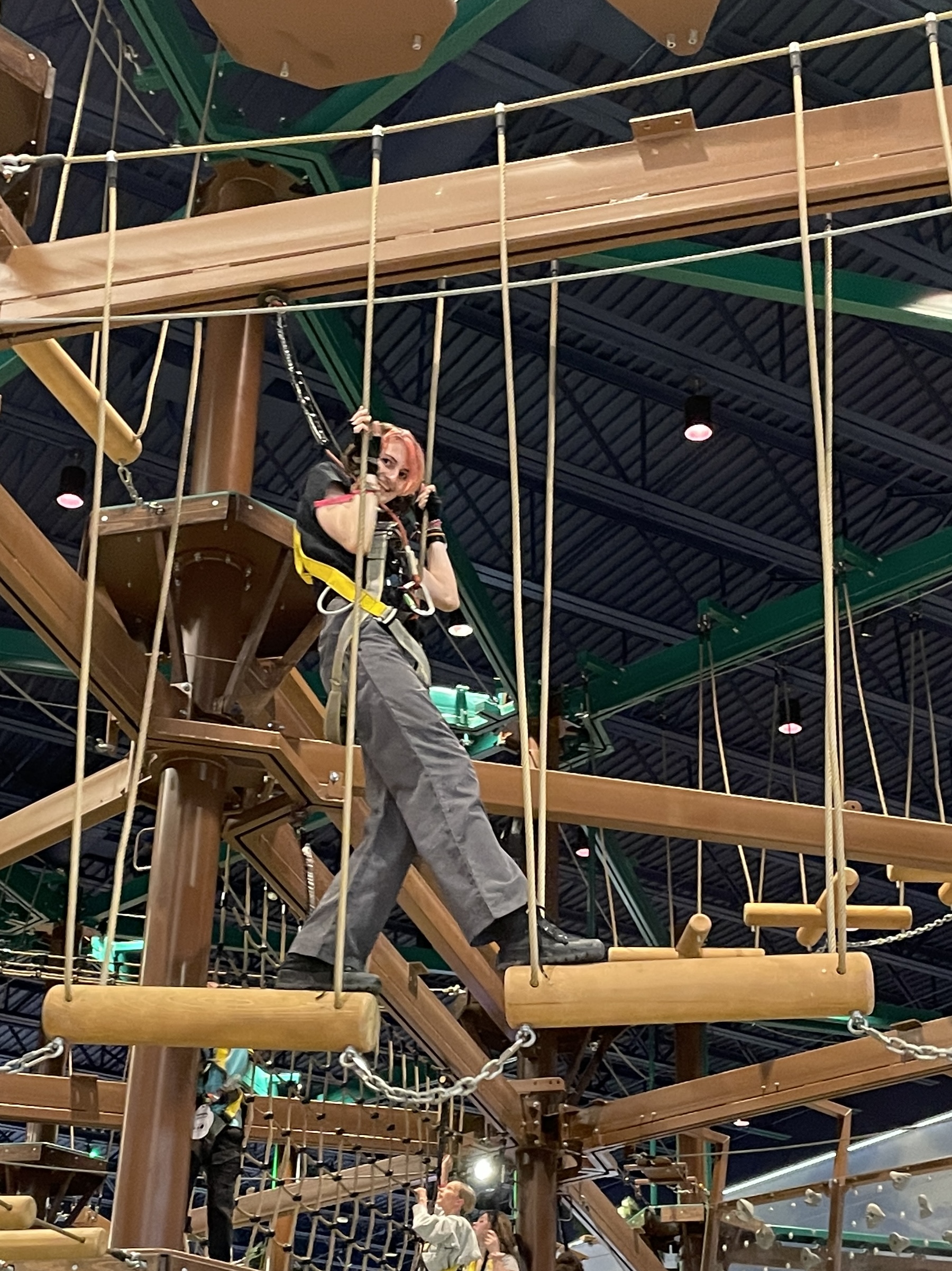 Abby is stepping from one trapeze to the next and smiling at the 
              photographer