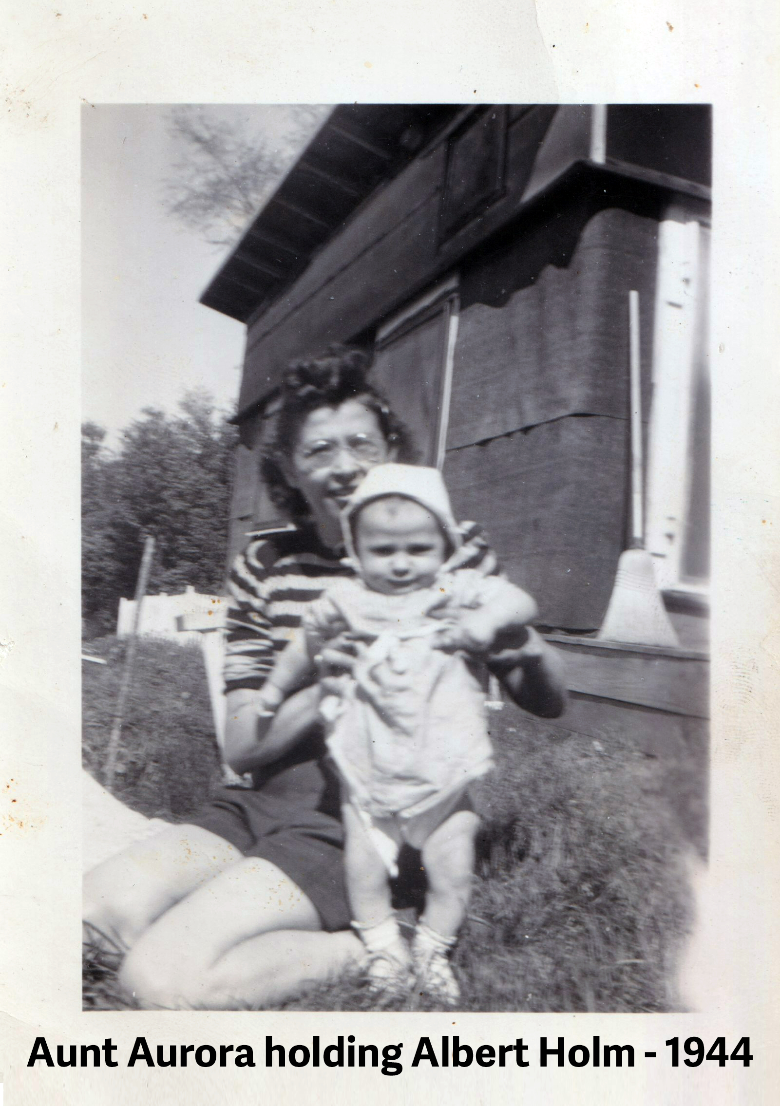 Both are looking at the camera. They are near a building with
          tar paper siding. 