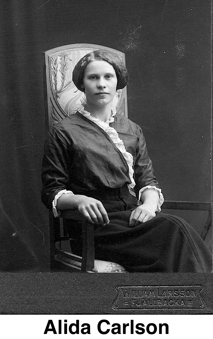 This is a studio photo with her wearing a dark dress with white trim 
         and sitting in a chair.