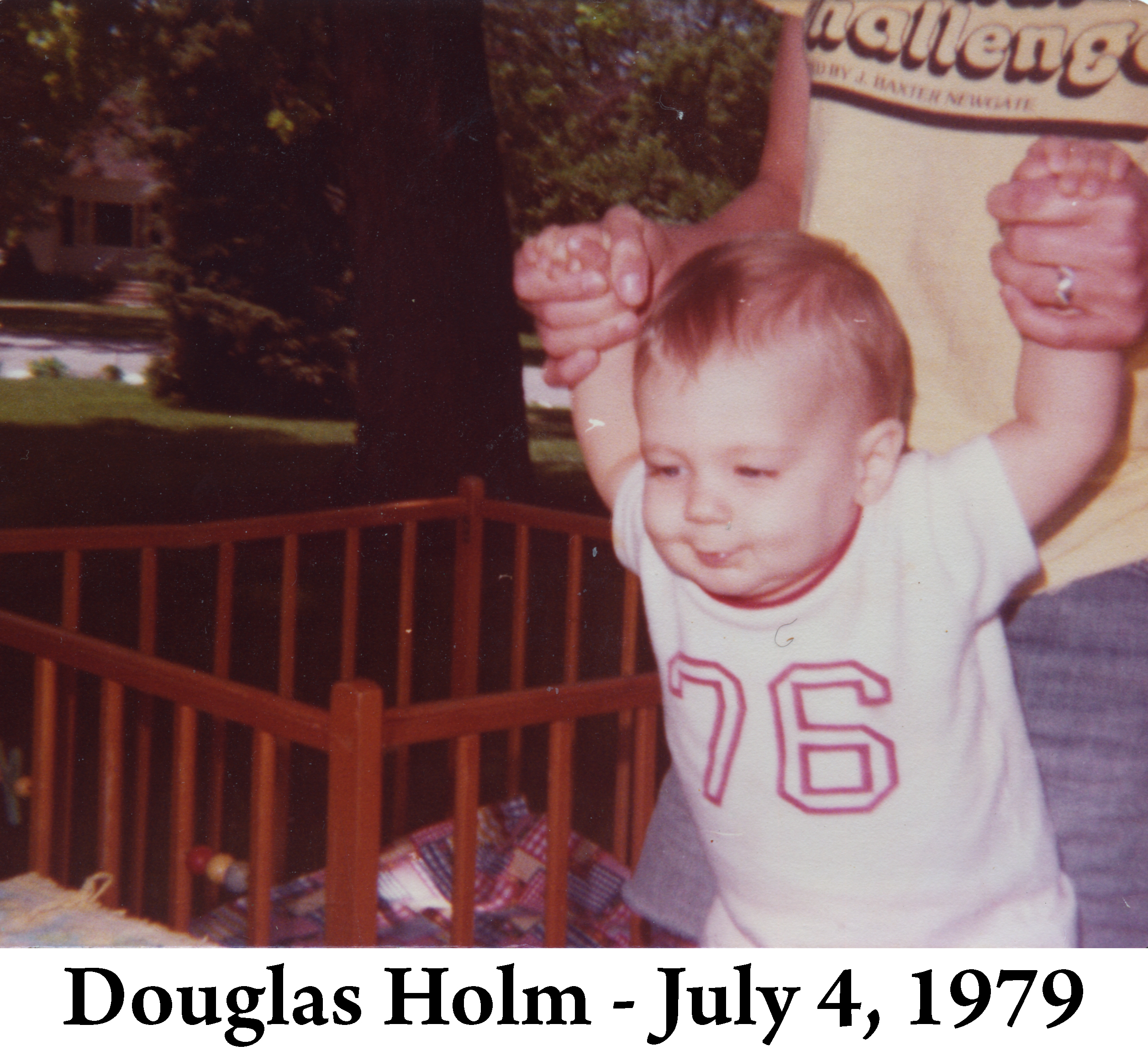 Gail is holding Doug’s hands in the yard of his Paton grandparents