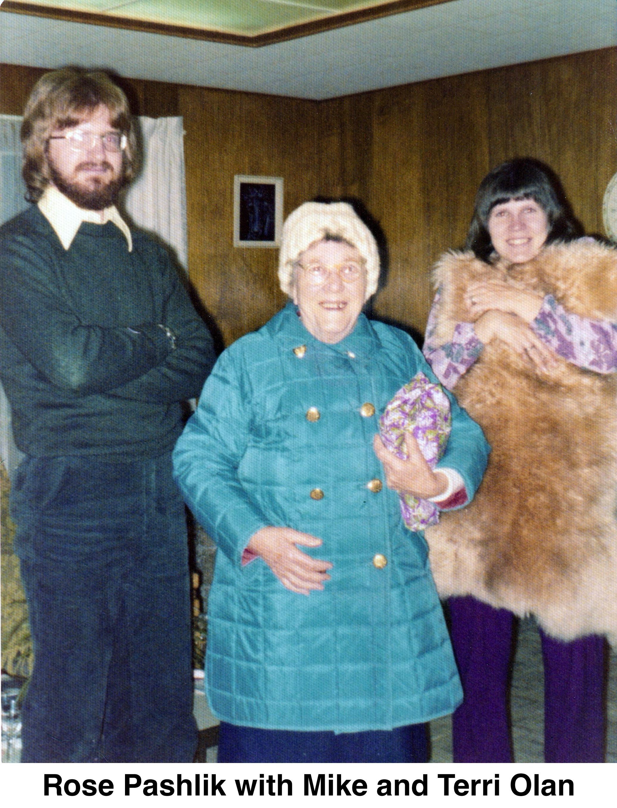 Rose is between Mike and terri in Carl and Helen Holm’s living room.
       She’s wearing a blue, quilted coat and a white cap.