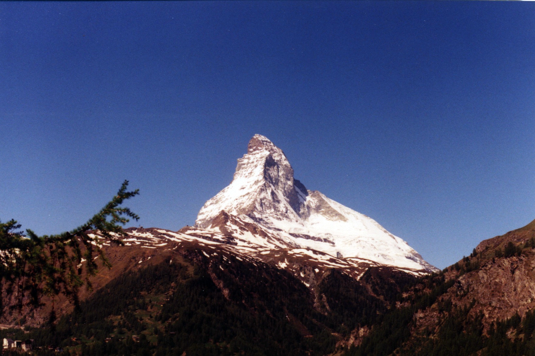 The Matterhorn mountain is silhouetted against a deep blue sky.