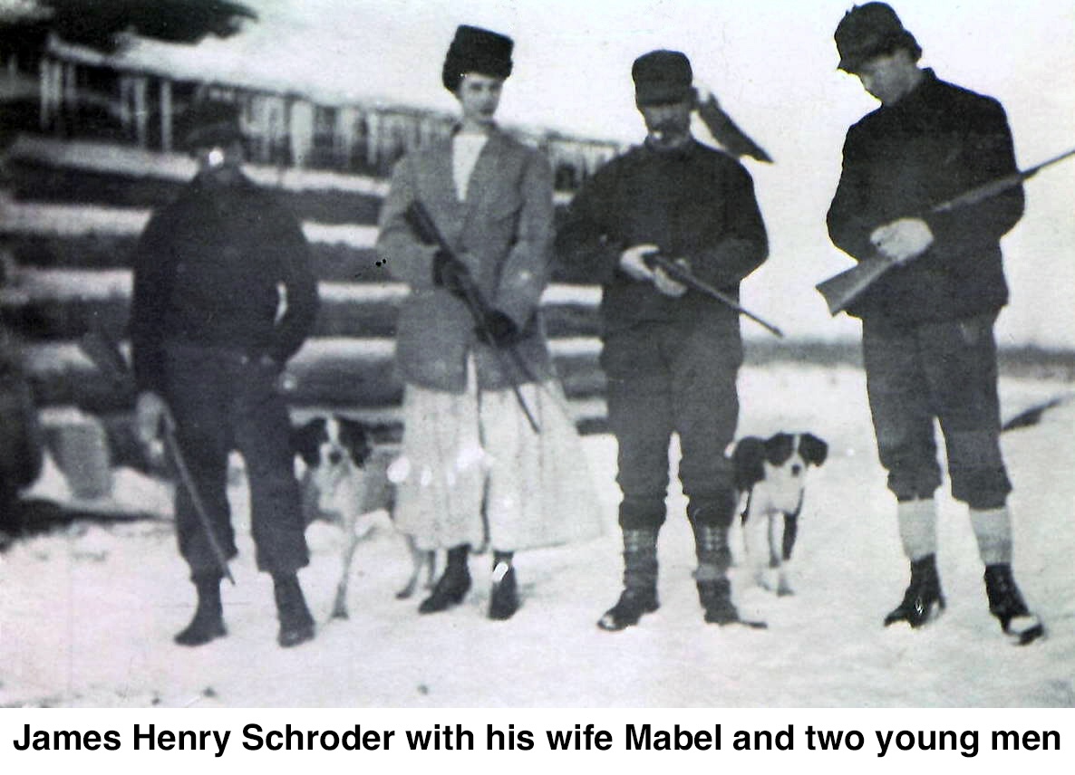 A bearded man smoking a pipe stands near the center of this winter photo. Next to
          him is a younger woman and there;s a young man on each side.
          All are holding rifles.