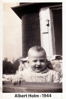 Albert Holm sits in a high chair outside a building