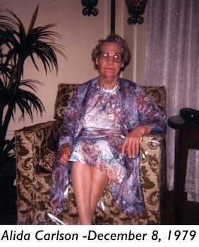 Alida Carlson is wearing a colorful dress and sitting in a upholstered chair