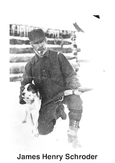 JamesHenrySchroder is kneeling on one knee, holding a rifle, and a dog. A log cabin 
       is in the background.