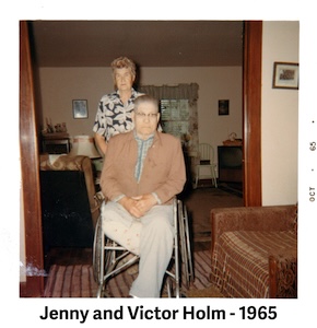 Victor Holm is sitting in his wheelchair and Jenny is standing behind him