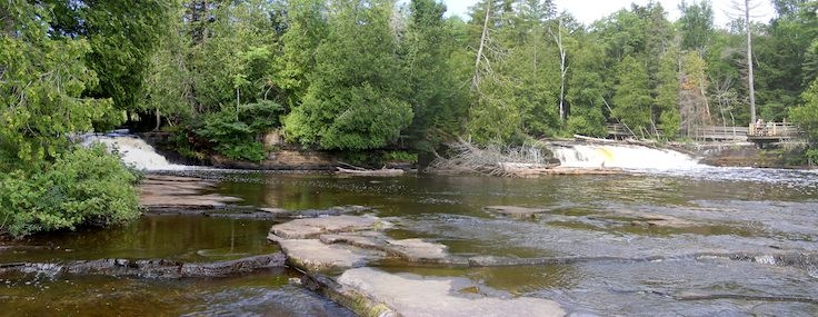 Two currents of one side of the falls flow over
               a six-foot drop. An island separates them.
               Some people view the falls from a platform on
               the right side of the picture.