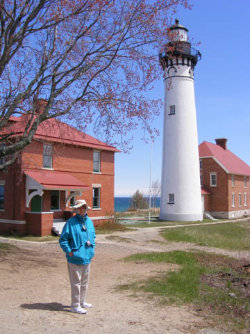 Gail standing in front of the Au Sable Light Station and its support buildings