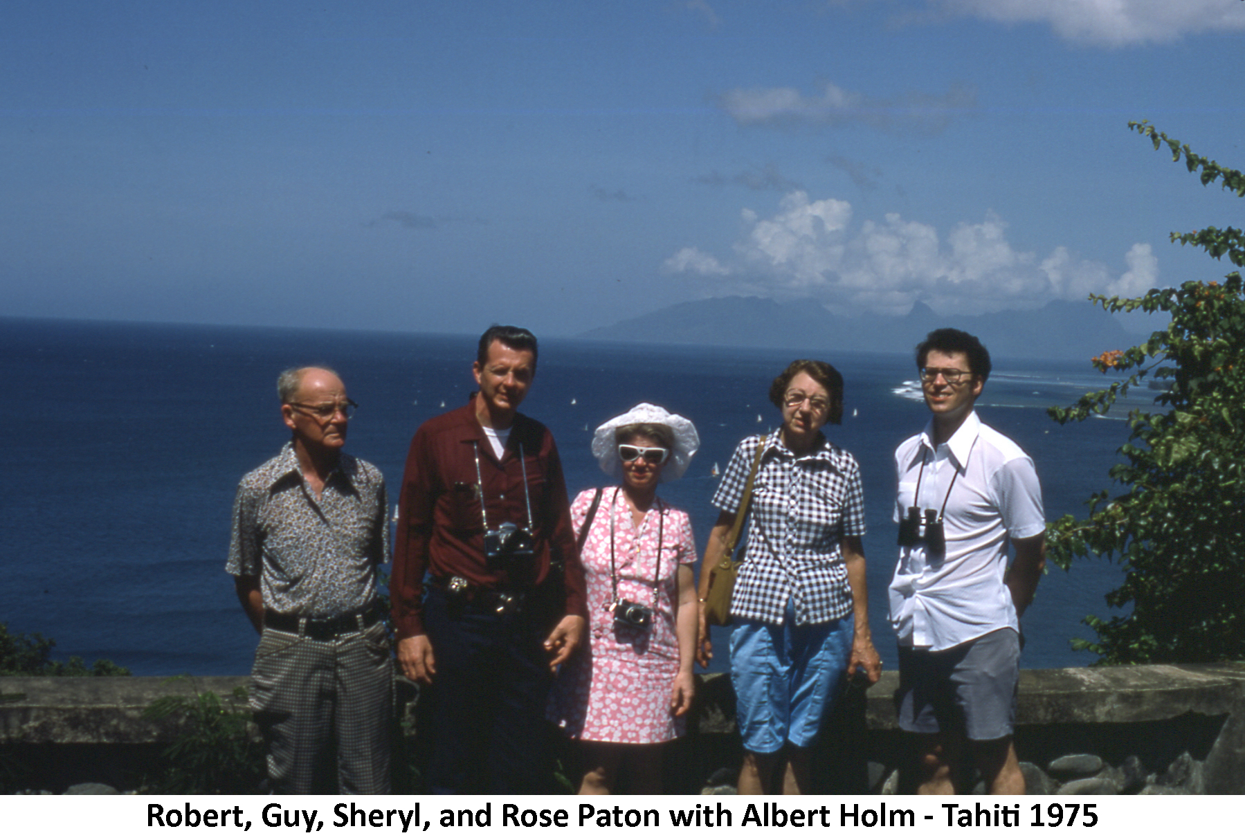 The Patons and Al Holm standing in front of a wall overlooking the ocean in Tahiti