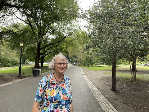 Gail is on a wide, paved path with trees on each side