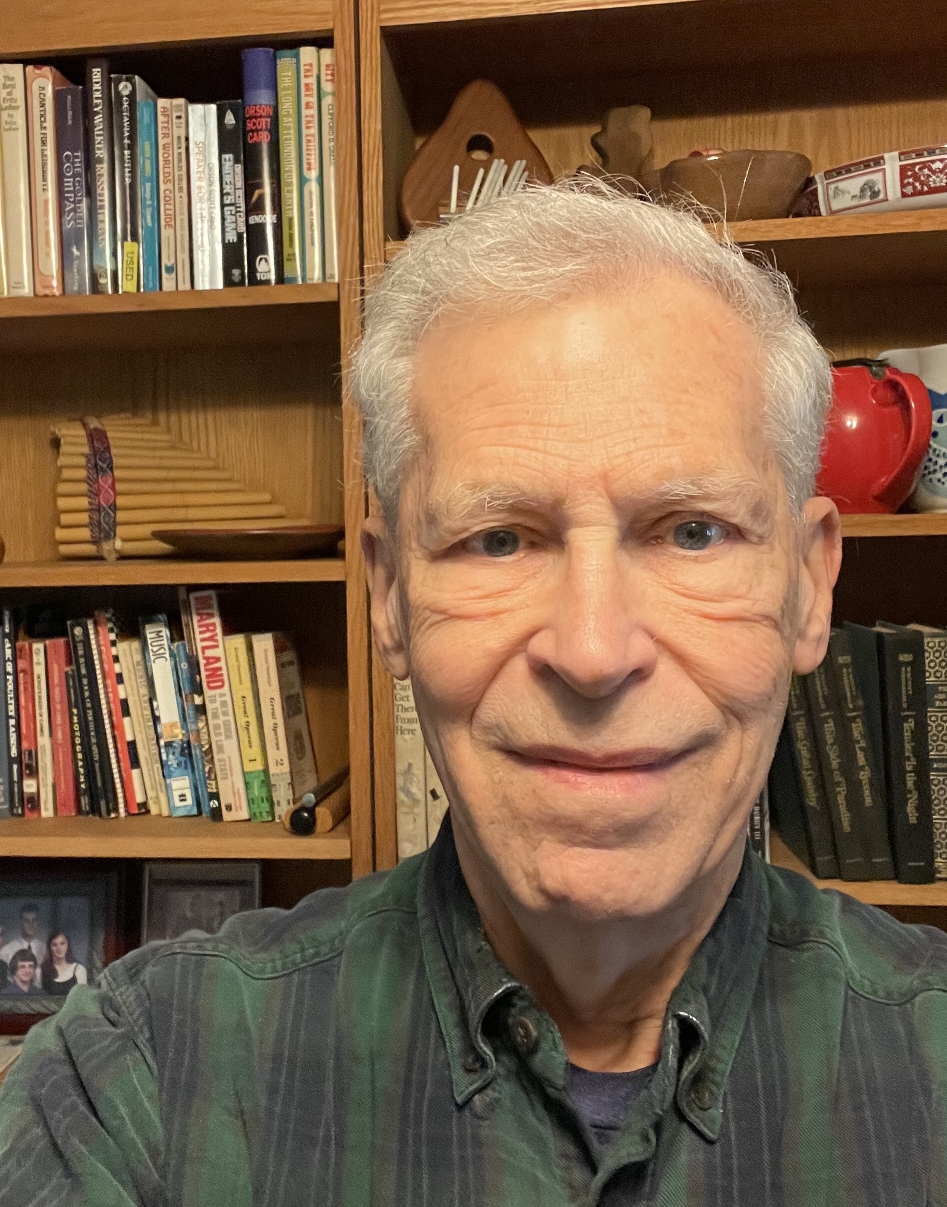 Albert Holm at 80 years old and standing in front of a bookcase 