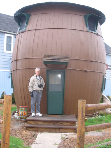 Al Holm standing at the door to a pickle barrel-shaped cottage in Grand Marais, Michigan.