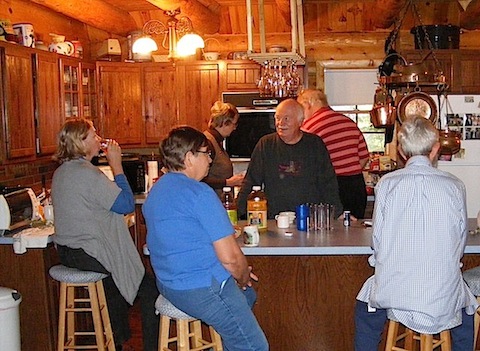 Folks gather around the                island in the kitchen for coffee and juice while Bob works               to prepare breakfast.