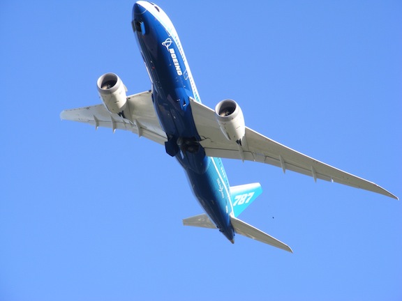 The plane is seen from below as it passes overhead.
               The nose is at the top of the image. The body of the 
               plane is painted white, dark blue and light blue. 