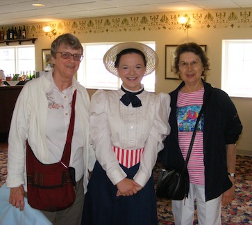 The picture is taken in the waiting room on
               the second level of the showboat. Gail and Julie
               flank the actress who is wearing a straw hat,
               white blouse, black skirt, peppermint-striped
               belt, and a black bow tie.