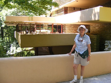 Gail stands on the walkway to 
               the entrance to the house. The tan-colored
               cantilevered terraces are behind her.