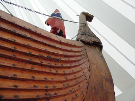 Seen from below, the prow of the replic
                 Viking ship rises high to the animal figure head.
                 The overlapping of the boards forming the
                 body of the boat is accentuated.