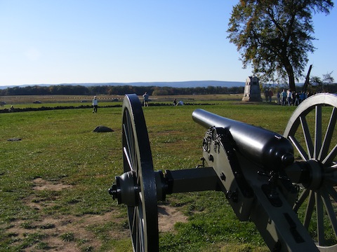 A cannon points from the Union positions at          the Angle across the fields where Pickett's division advanced          toward the trees in the far distance where they started.