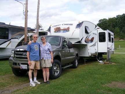Al and Gail standing in front of their F-250 tow
               truck and Copper Canyon 5th wheel trailer, on a flat
               field at the Fox Den Campgound in New Stanton, PA.